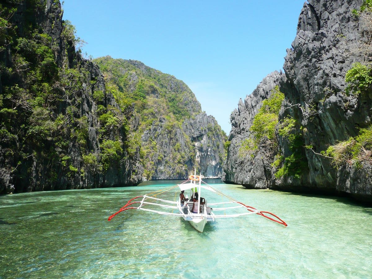 boat coasting along river between limestone cliff